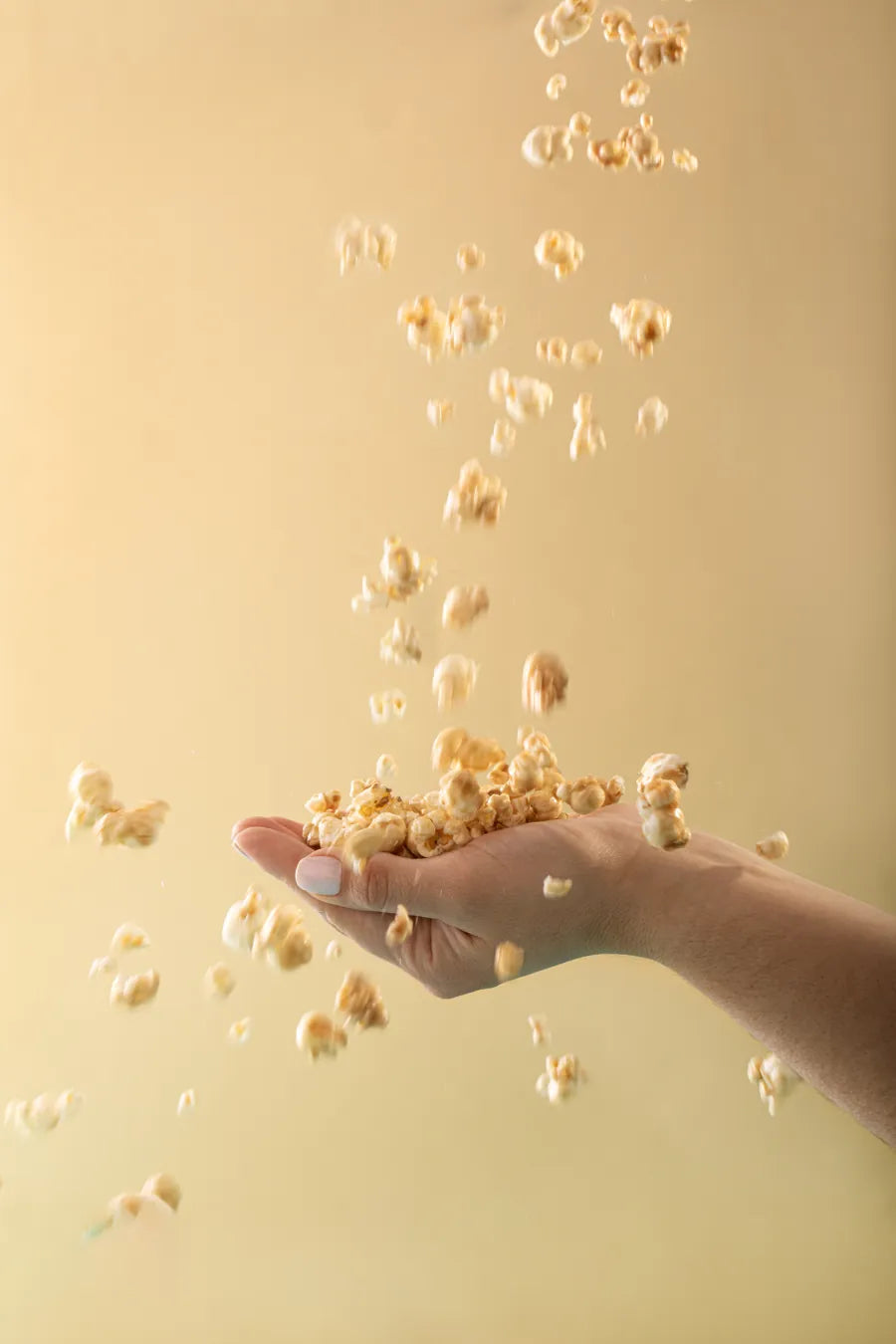 Mão segurando Pipoca Zero YASY com pipocas caindo